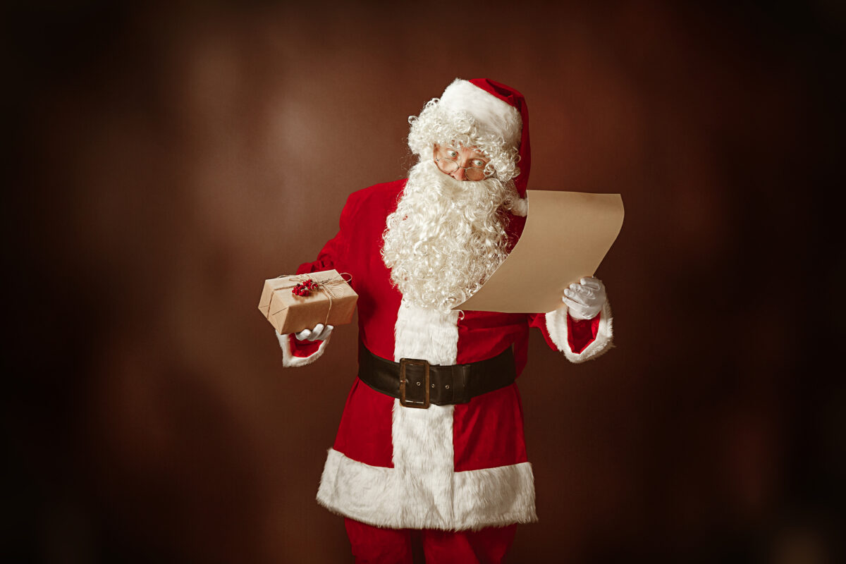 portrait-man-santa-claus-costume-with-luxurious-white-beard-santa-s-hat-red-costume-reading-letter-red-studio-background-with-gifts-1200x800.jpg